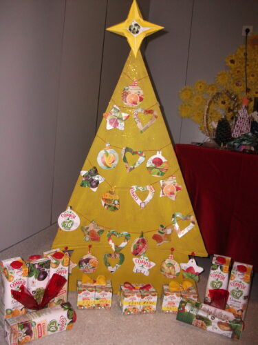 Árvore de Natal da Compal exposta no Hall de entrada da escola, junto à mesa de trabalhos de Natal feitos com materiais reciclados pelos alunos em família.