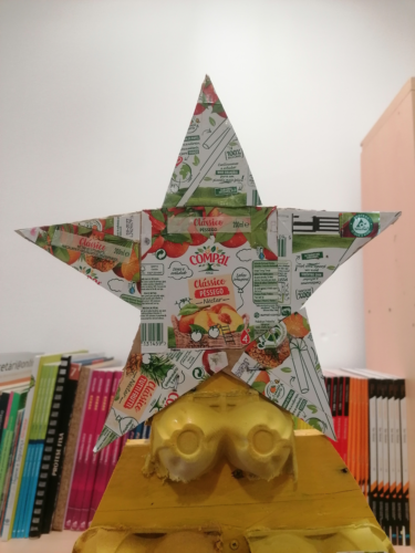 Estrela da árvore de Natal predominantemente amarela, com embalagens da Tetra pak, Símbolos FSC e materiais reutilizáveis.