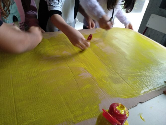 O primeiro grupo de alunos estão iniciando as pinturas da cartolina em amarelo.
