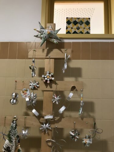 Pormenor da parte superior da árvore de natal decorada com enfeites construídos a partir de embalagens da Compal