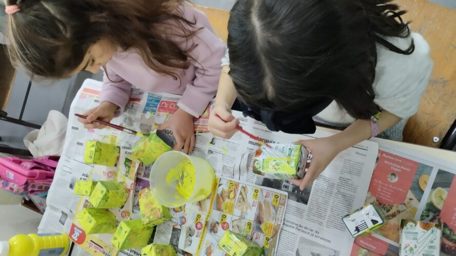 Os alunos depois de lavarem os pacotes, com a ajuda de uma funcionária, estiveram a pintá-los de amarelo - tinta acrílica.