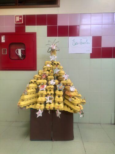 Título: A árvore amarela do Natal<br/>Descrição: Esta árvore tem como base caixas de ovos, pintadas de amarelo, com guaches, durante as aulas. Foram feitas estrelas e bolas como decoração, em embalagens de compal.