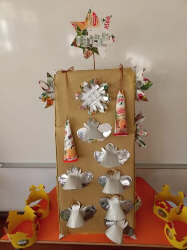 Foto da árvore junto das coroas de reis (decoradas também com recortes de embalagens de compal e recortes de folhetos de supermercado).