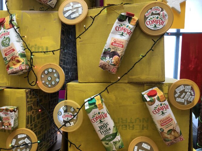 Na nossa árvore Amarela de caixas de cartão, foram colocados os enfeites: embalagens Tetra Pack da Compal, coladas e bolas de natal - tampas latas de leite para bébés - com os diferentes símbolos/selos e também com a palavra Compal das embalagens : )