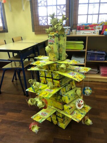 Resultado final da árvore de Natal amarela, construída com embalagens da Compal. Para complementar as crianças utilizaram caixas de ovos, caixas de cereais, tinta guache amarela, fio de lã, cola e lápis/canetas de colorir.