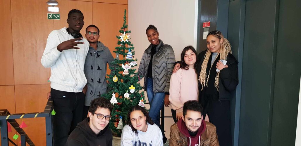 Foto da árvore de Natal no espaço da escola, alunos da escola junto à árvore de Natal