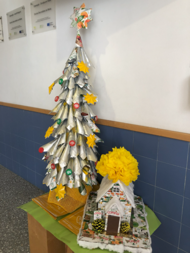 Trabalho final: uma árvore de Natal amarela elaborada com "cartuchos" e uma casinha de Natal, elaborados com pacotes de embalagens tetrapack da Compal