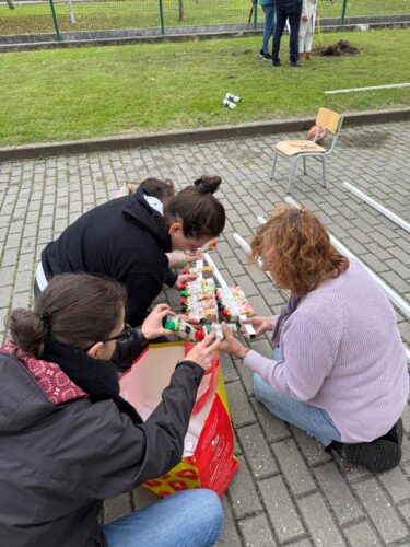 Após a seleção e limpeza das embalagens, cada pacote foi furado de forma a permitir a sua fixação na armação em ferro. Os alunos e os pais encaixaram as embalagens na armação de ferro.