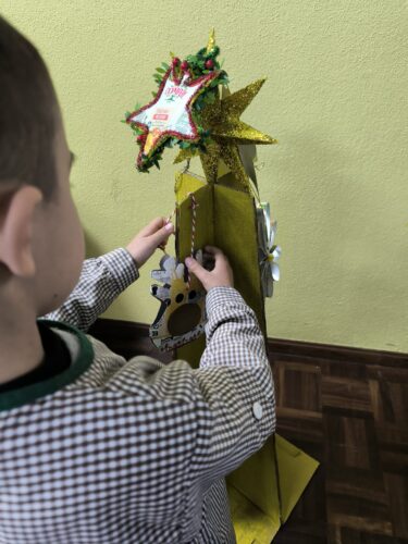 Alunos a decorarem a arvore com os enfeites construídos em casa;