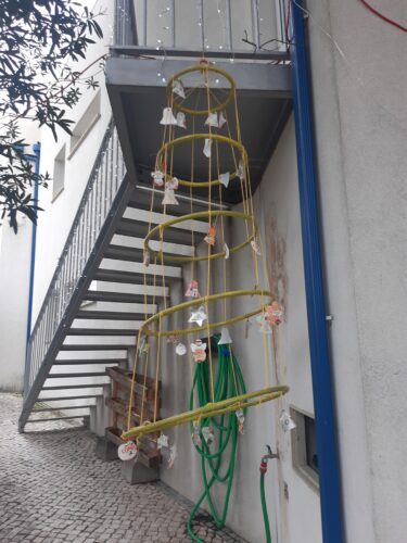 Árvore pendurada na escada junto à entrada.