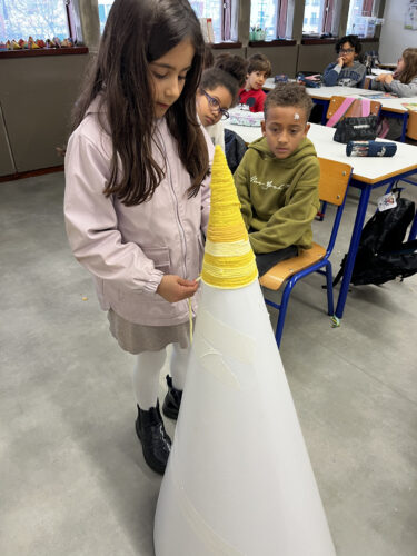 Aluna a "tecer" com trapilho amarelo, de forma a dar a cor amarela ao cone de cartão.
