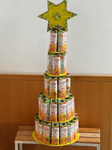 A árvore de Natal Amarelo da Compal concluída. No cimo a estrela de cor amarela contornada com os símbolos da Tetra Pak e ainda com algumas estrelas coladas, decalcadas nas imagens de frutos mais amarelos para realçar a cor.
