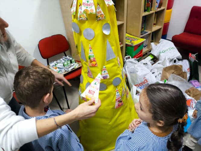 Crianças e adultos, juntos, decoram a Árvore de Natal.