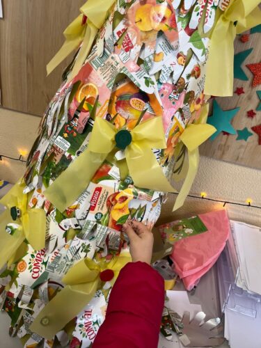 Colocação na árvore das mãos por parte de cada aluno. Juntaram-se laços amarelos com a tampa da embalagem no centro.