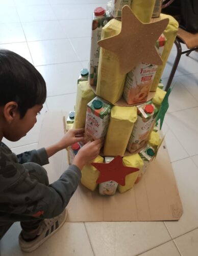 Aluno a colocar e colar uma embalagem da Compal de modo a construir a Árvore de Natal.