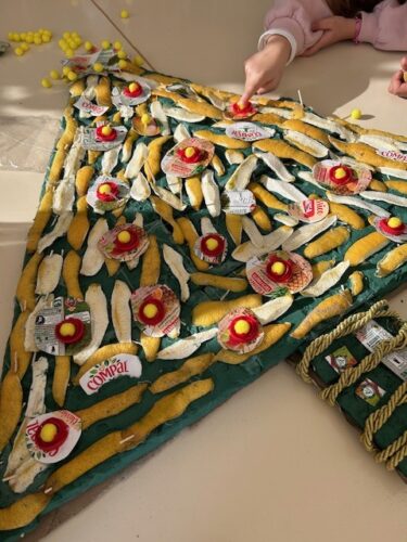 Árvore quase completa com as colagens das bolas em tetra pack da Compal, aproveitamento das tampinhas e cordão reutilizado de ramos de flores