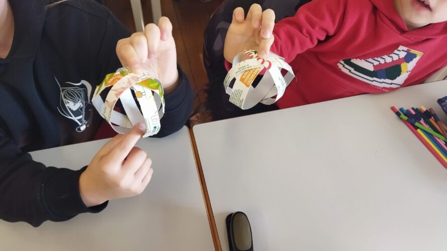 Os alunos mais novos fizeram bolas e estrelas ambas em 3 D das embalagens de sumo pequenas..