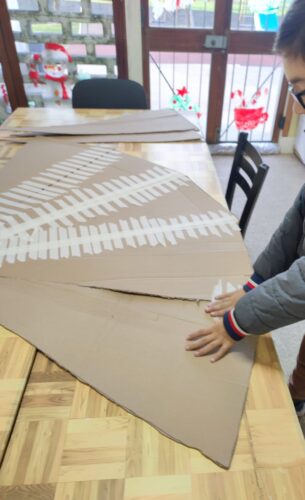 Depois de decidido em conjunto com os alunos o trabalho a realizar, fez-se a recolha dos materiais.<br/>Iniciou-se o trabalho com o recorte do cartão em triângulos e sua colagem com fita de papel e cola quente.