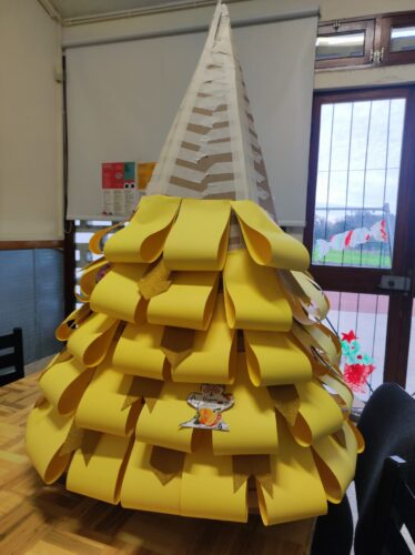 Recortou-se cartolinas amarelas e douradas em retângulos e foi-se colando no cartão.