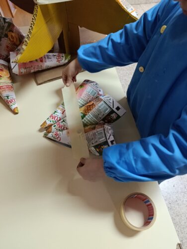 Preparação e decoração da arvore com cones feitos de embalagens.