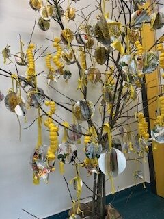 Decoração da árvore de Natal, onde se evidenciam as bolas decorativas realizadas com embalagens Tetra Pak da marca Compal e os “cordões” realizados com tampas amarelas de embalagens.