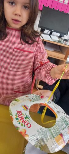 Enfiar fita amarela, com o auxílio de uma agulha de plástico, para segurar as várias camadas da árvore.