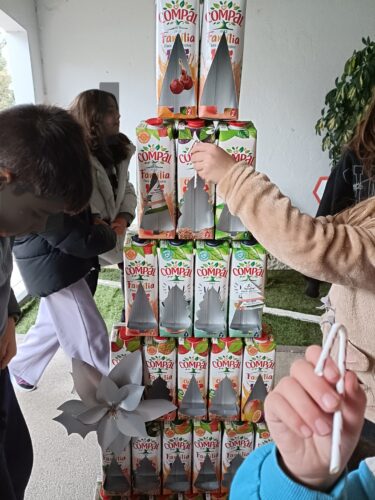 Damos brilho à nossa Árvore <br/>Aplicámos os vários elementos decorativos, para que a nossa árvore ficasse completa e encantadora.<br/>Material: embalagens Tetra Pak da marca Compal, adereços construídos, fio de pesca, fita-cola, tintas.