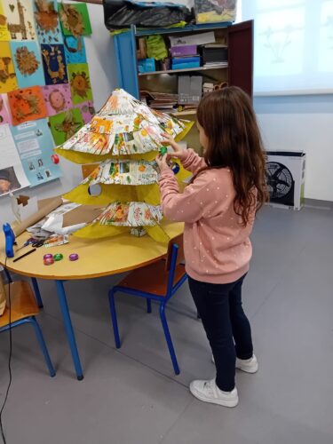 Processo de construção: Aluna a pendurar as tampas(decoração) na árvore.