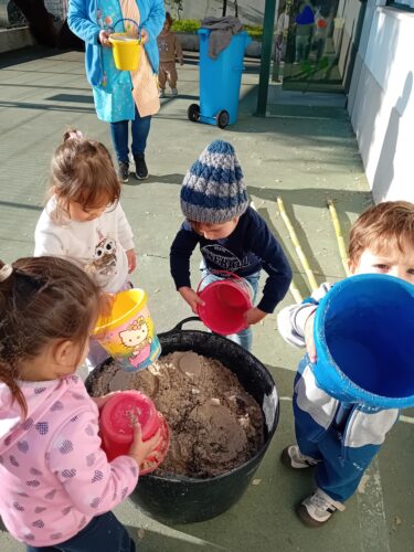 Construção da base da Árvore de Natal com a colaboração das crianças<br/>As crianças colaboraram transportando e colocando a terra para criar uma base segura para a árvore, promovendo o trabalho cooperativo, a responsabilidade e contacto com material natural