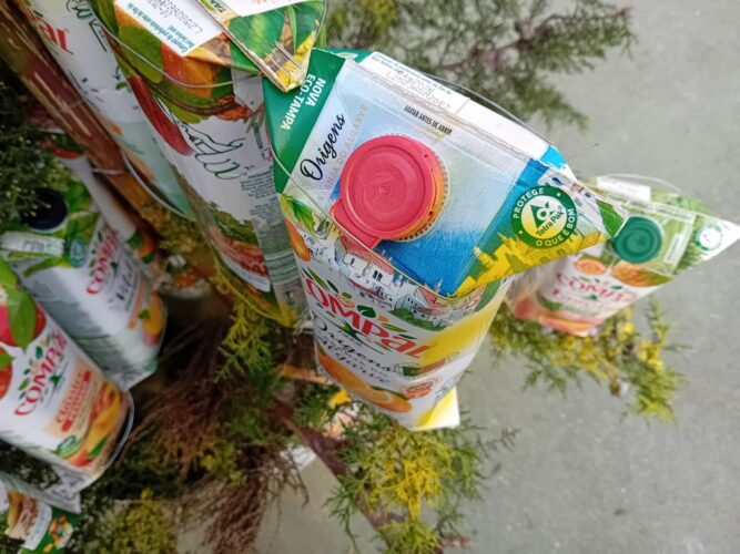 Reutilização criativa de embalagens Compal em estrutura decorativa<br/>Detalhe da reutilização criativa de embalagens Tetra Pak da marca Compal na construção da estrutura decorativa da Árvore de Natal Amarela. Observam-se claramente os símbolos da Tetra Pak