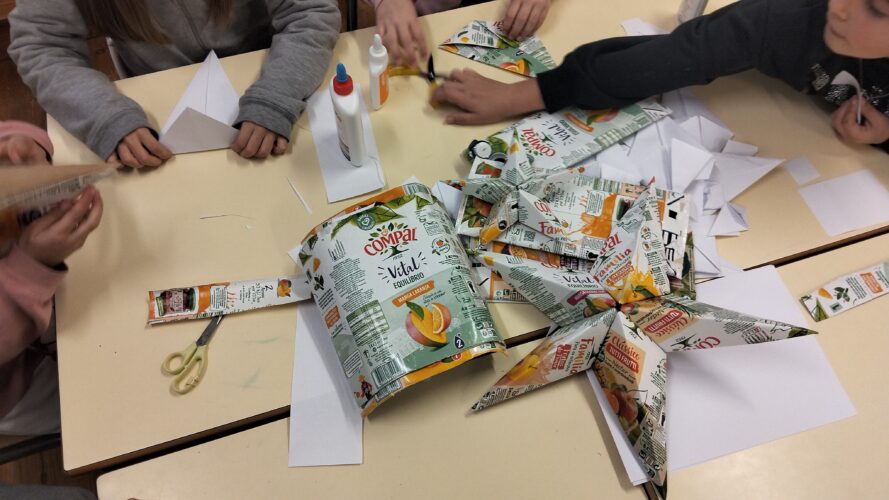 Aqui, podemos observar a dobragem das peças de origami. Cada estrela é feita com cinco peças de origami, ou seja, cada estrela precisa de cinco embalagens.