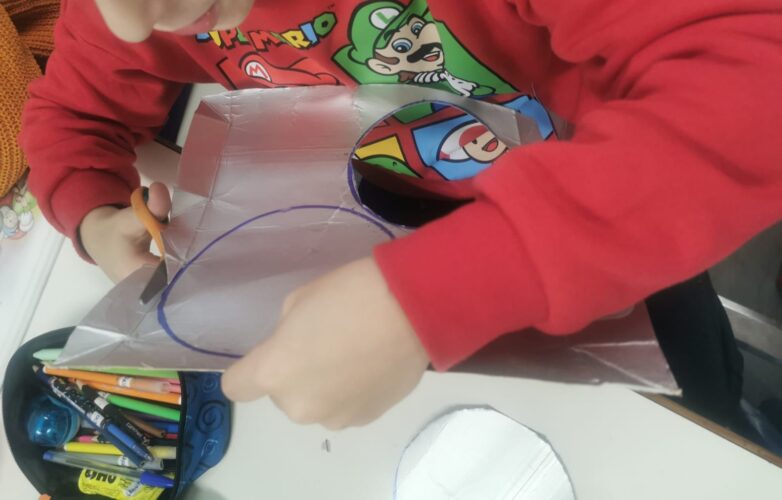 Recorte de bolas de Natal em material Tetra Pack para posterior colagem de palavras alusivas ao Natal e à solidariedade( papel de jornal).