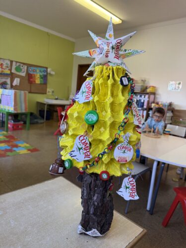Árvore com símbolos Tetra Pak e Compal ( apresentado de várias formas, em decoração de bolas, sinos, estrela, em tampas, nos sinos, e no bordado elaborado no tronco da árvore).