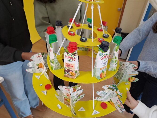 Uma árvore construída com resíduos de materiais escolares e de embalagens da Compal, recolhidas no ambiente escolar, adaptadas ao tema " Natal Amarelo 2025".