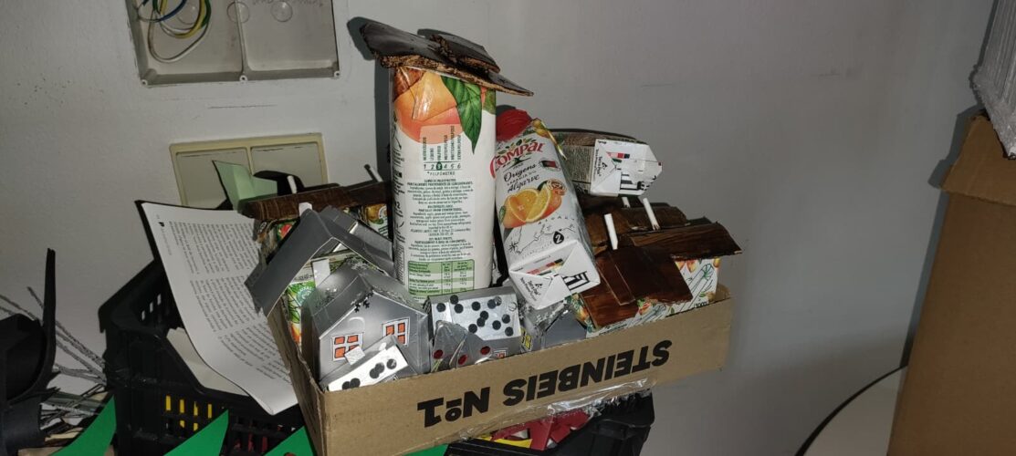 Construção das casas da aldeia em Tetra Pak Compal, com telhados de madeira reciclada e canas.