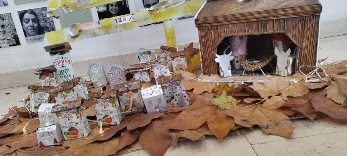 Aldeia/presépio integralmente construído com embalagens recicladas, a ser colocado na base da árvore, onde se podem visualizar os símbolos da Compal e Tetra Pak, amiúde.