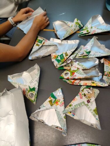 Os alunos lavaram as embalagens e recortaram-nas. Depois dobraram-nas em triangulo