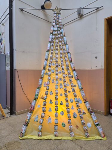 A árvore foi construída com embalagens inteiras, enfiadas em fio do norte. Nos cantos da árvore estão embalagens familiares. O amarelo foi conseguido com sacos de lixo. A estrela do topo foi construída pelos alunos do ensino especial.