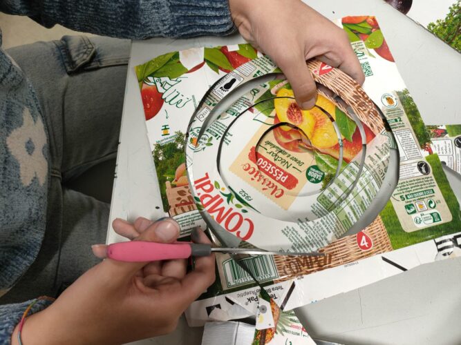 Aluno a recortar espiral bicêntrica dando destaque ao símbolo “Compal”