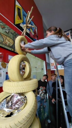Nesta imagem os alunos terminaram a montagem dos pneus e iniciaram a decoração com papel metalizado das embalagens dos painéis interativos e com as embalagens da Compal transformadas em enfeites.