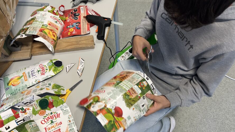 Embalagens- Recorte, realização/ construção da Árvore Amarela. A imagem apresenta o nosso aluno a recortar as embalagens de forma planeada para dar o efeito de ramos/ estrutura da árvore.