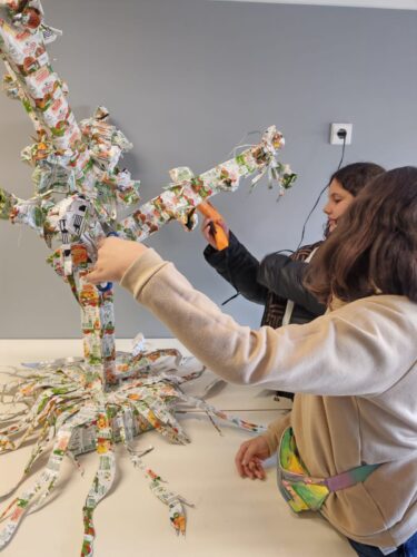 Montagem colaborativa da estrutura da árvore com embalagens reutilizadas.