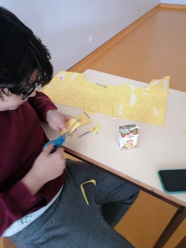 Marcação e recorte de figuras natalícias em cartolinas amarelas e embalagens compal.