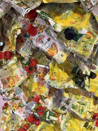 Utilização de embalagens Tetra Pak da marca Compal<br/>Detalhe da aplicação das embalagens Tetra Pak da marca Compal na Árvore de Natal, com os símbolos Tetra Pak e Compal visíveis.