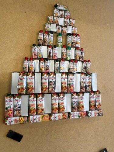 Detalhe das embalagens Tetra Pak da marca Compal utilizadas na árvore, evidenciando os símbolos da Tetra Pak e da marca, bem como diferentes formas de reutilização.