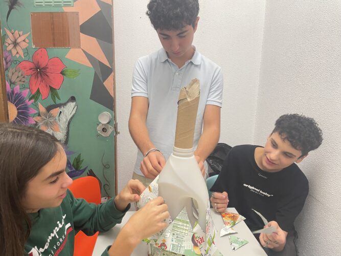 Processo1_Colar<br/>Alunos a colarem os triângulos na embalagem de plástico que serviu de estrutura.