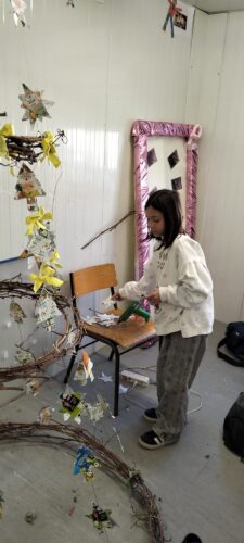 Alunos a aplicar estrelas, fitas e elementos decorativos produzidos com embalagens Tetra Pak e materiais naturais, consolidando cada nível da estrutura da árvore.